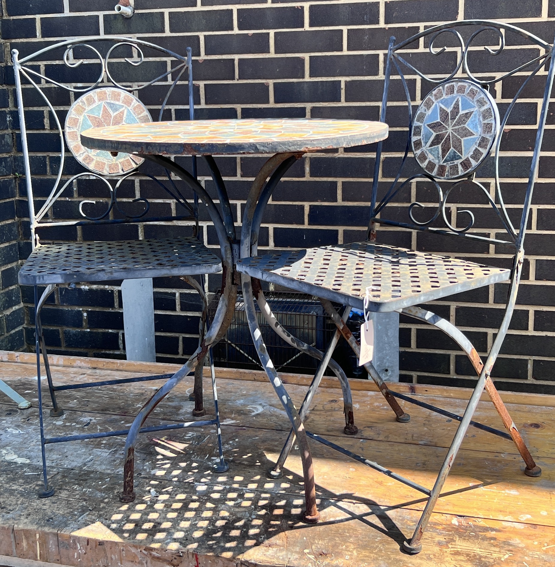 A circular mosaic topped garden table, diameter 60cm, height 73cm, and a pair of matching folding chairs